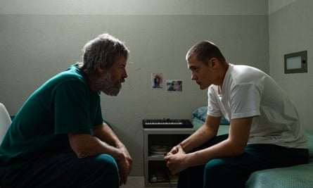 Guy Pearce and Vincent Miller sit face to face in a jail cell