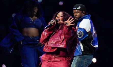 woman in red sings as a man performs behind her