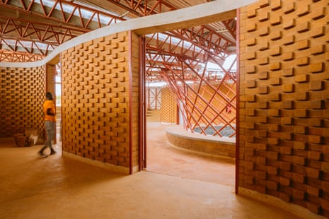 A man walks through an open-plan space with orangey red coloured walls