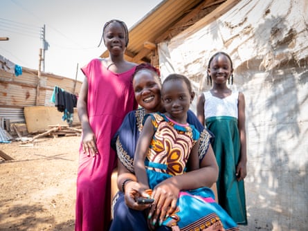 A woman sits with a young girl in her lap and two others behind her, on at each shoulder.