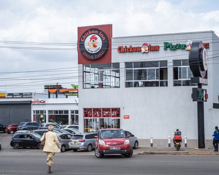 Cars parked outside a building with signs saying ‘chicken inn’ and ‘pizza’