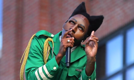 Tyler, the Creator, dressed in a green tunic, performs with a mic live in Boston, Massachusetts.