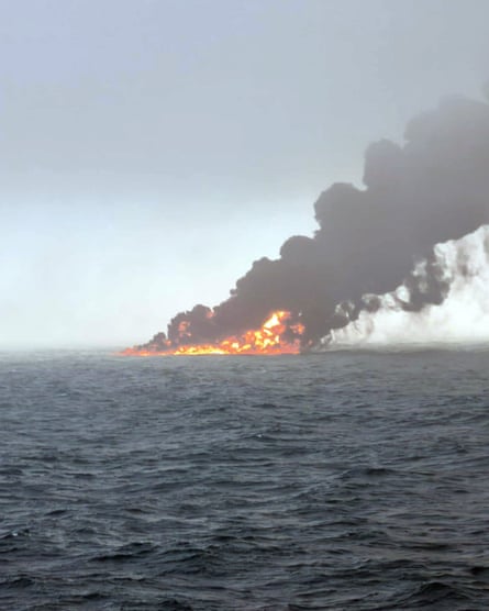 Black smoke billows into the air from flames that obscure the ships