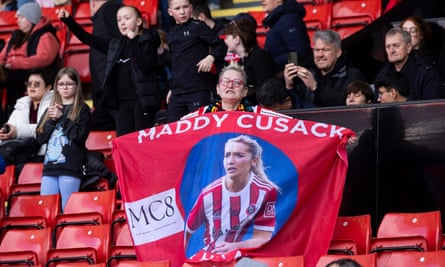 A fan holds a banner with a photo of Maddy Cusack