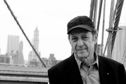 Steve Reich posing for a photo next to a bridge with Manhattan in the background