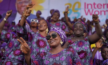 Women in a stadium crowd smile and sing