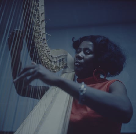 a woman wearing orange plays the harp