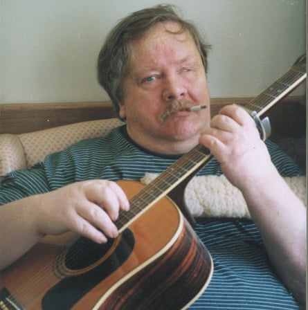 person wearing striped shirt smokes a cigarette while playing a guitar