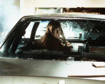 A girl looks frightened in a car with shattered windscreen