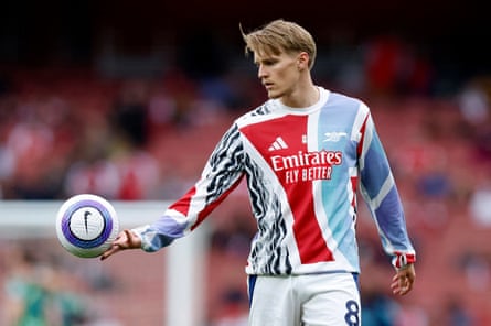 Martin Ødegaard of Arsenal wearing red, white and blue training kit and holding a football in his right hand.